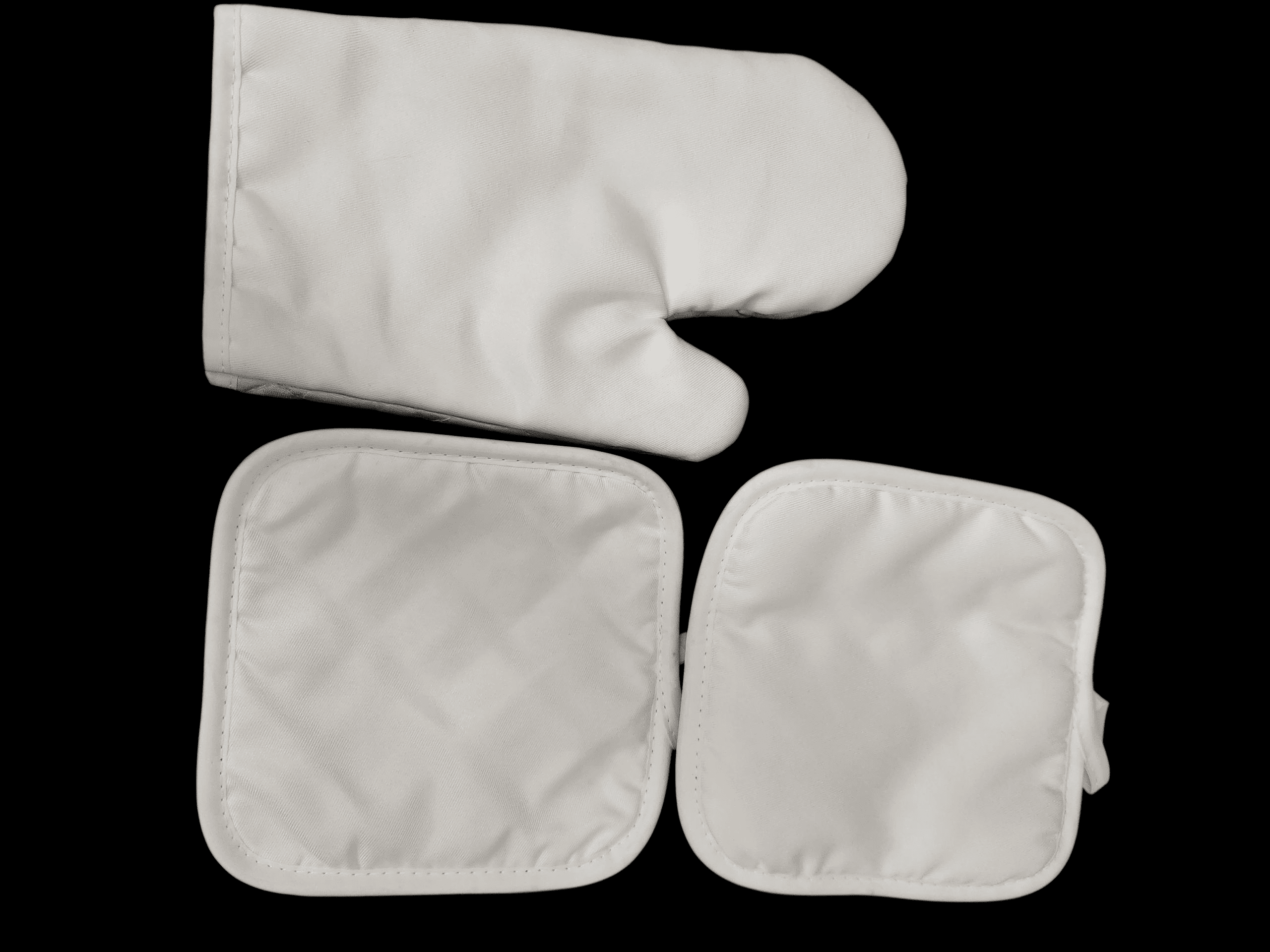 White quilted oven mitt and two matching pot holders on black background.