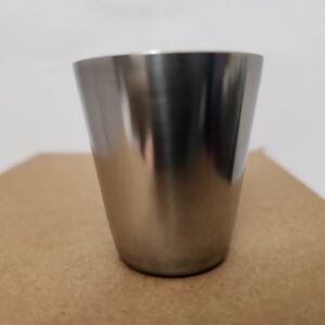 A shiny stainless steel cup on a brown surface.