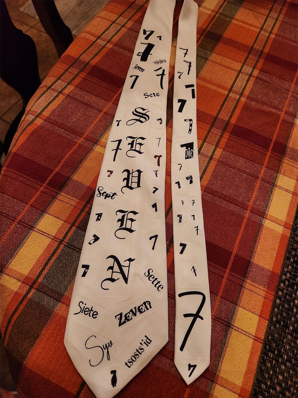 White scarf with "SEVEN" and number 7 printed in black.
