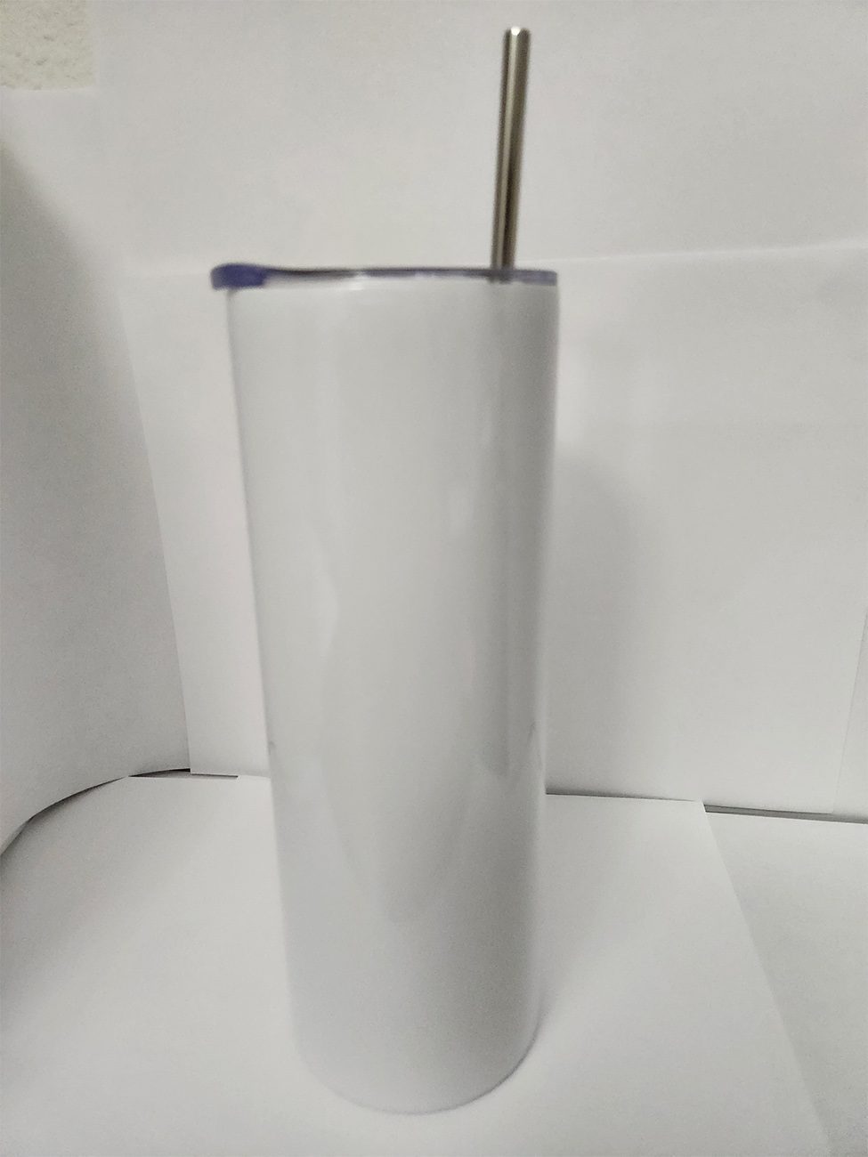 Tall white insulated tumbler with a straw on a white surface.