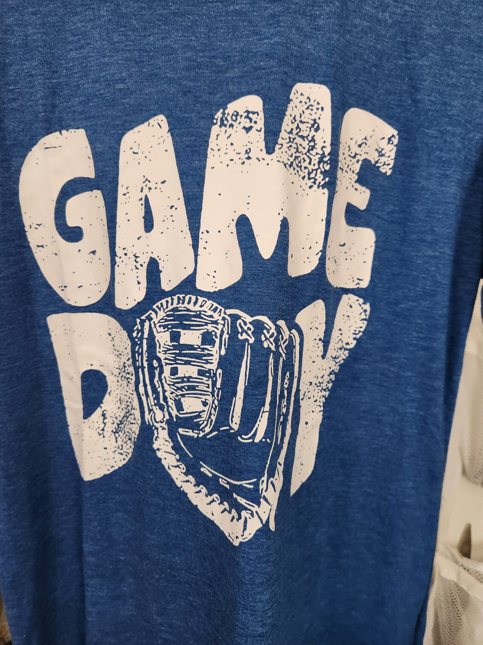 Close-up of a blue shirt with the text 'GAME DAY' and a baseball glove graphic.