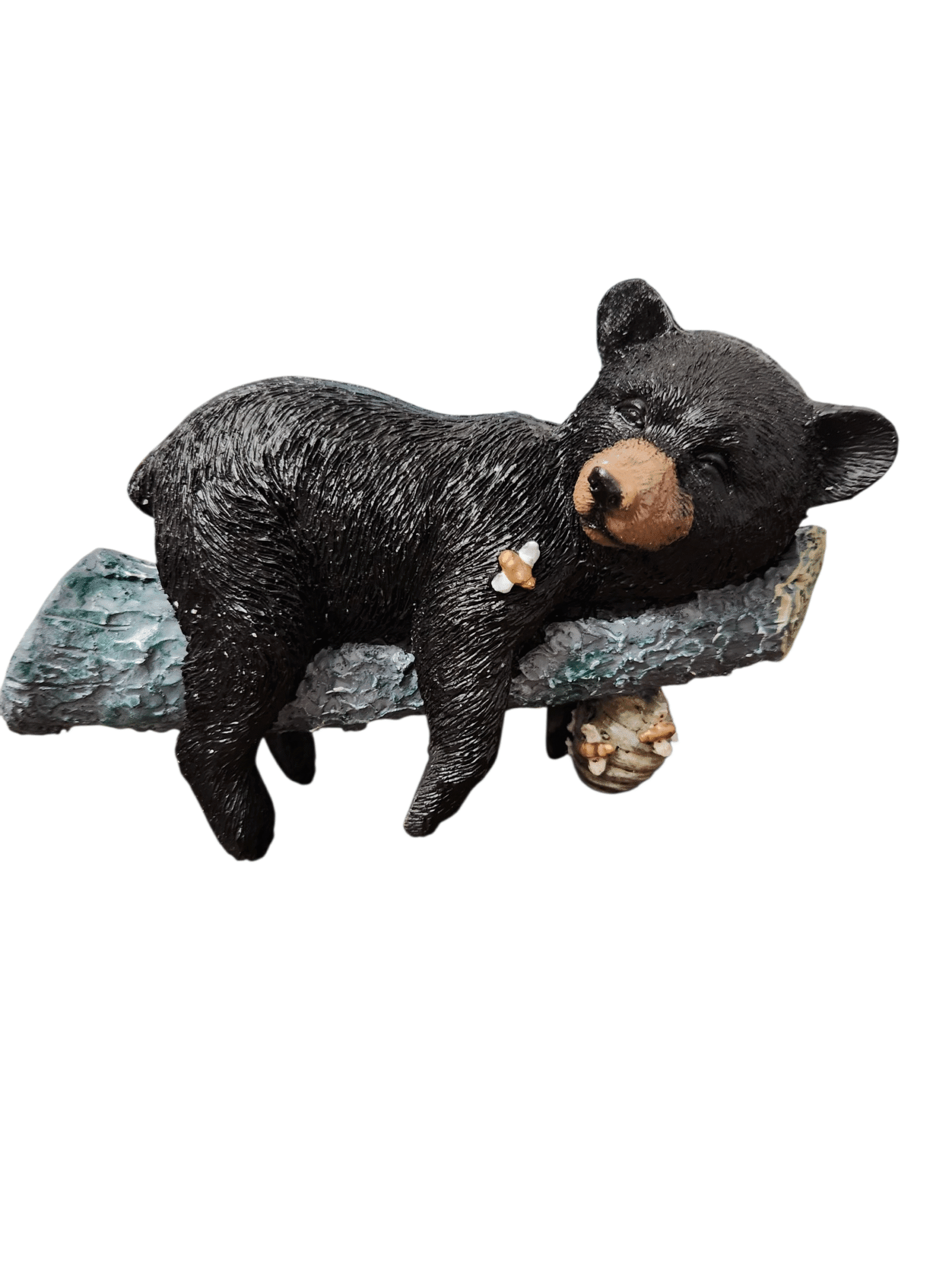 A cute black bear figurine sleeping on a tree branch.