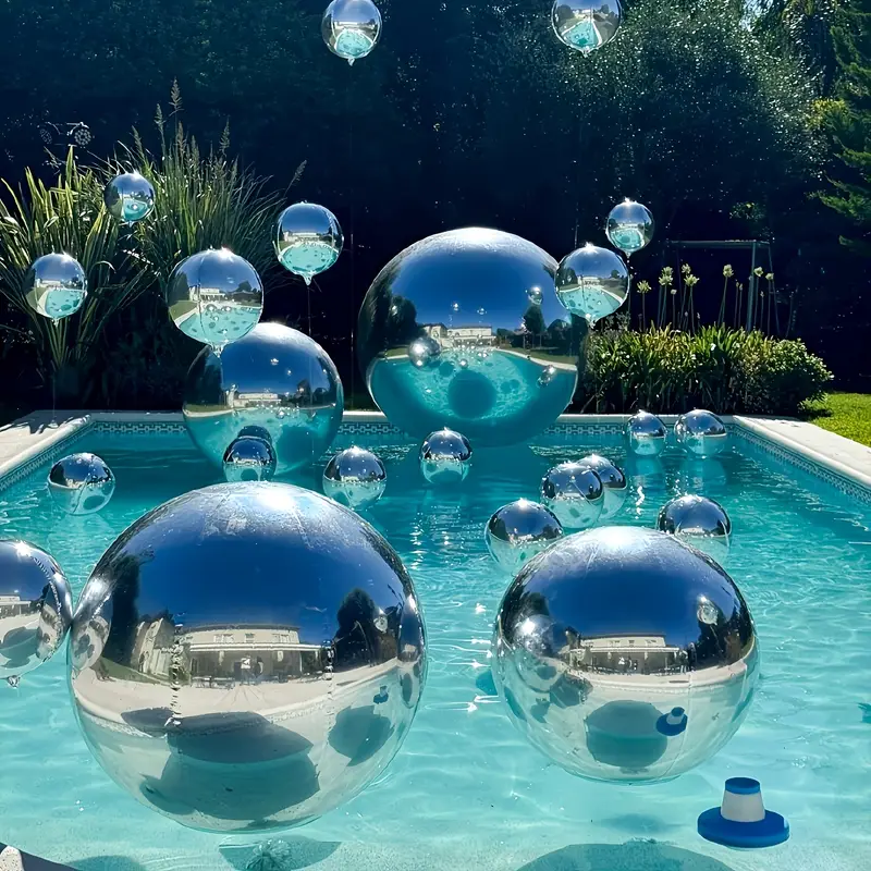 Reflective silver spheres float in a serene blue pool under sunlight.