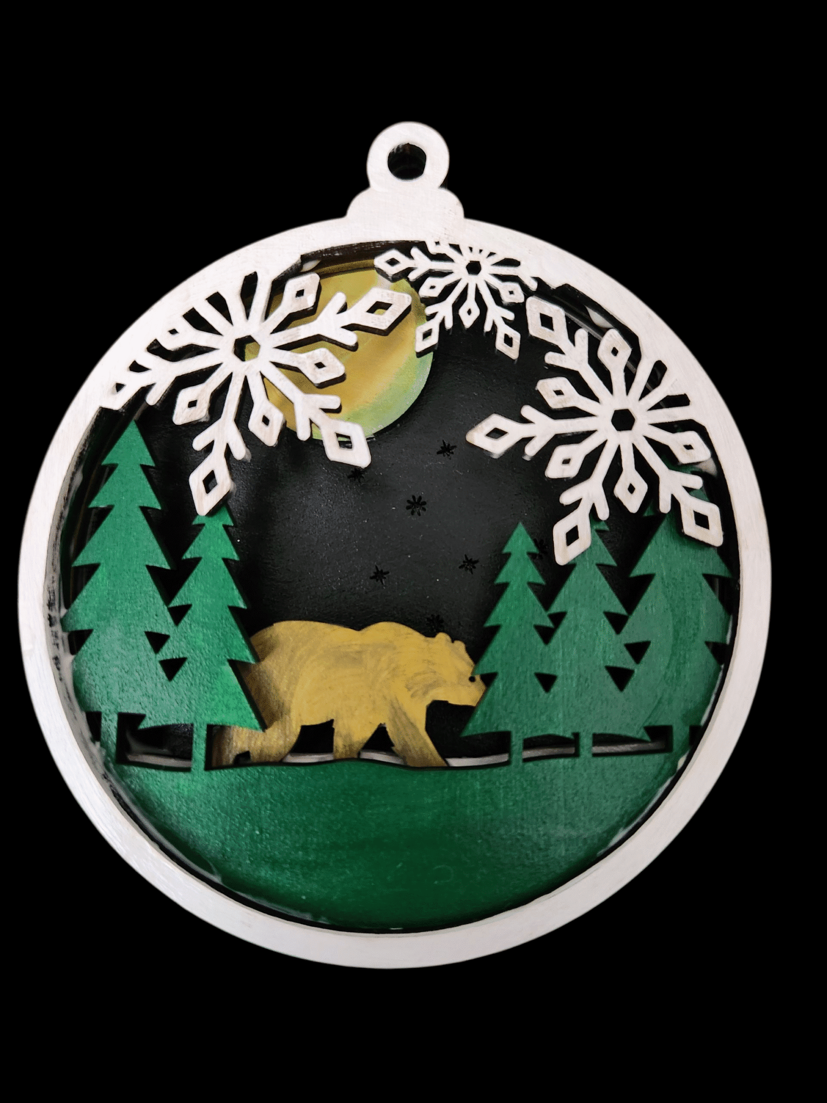 Decorative ornament featuring a bear and pine trees with snowflakes.