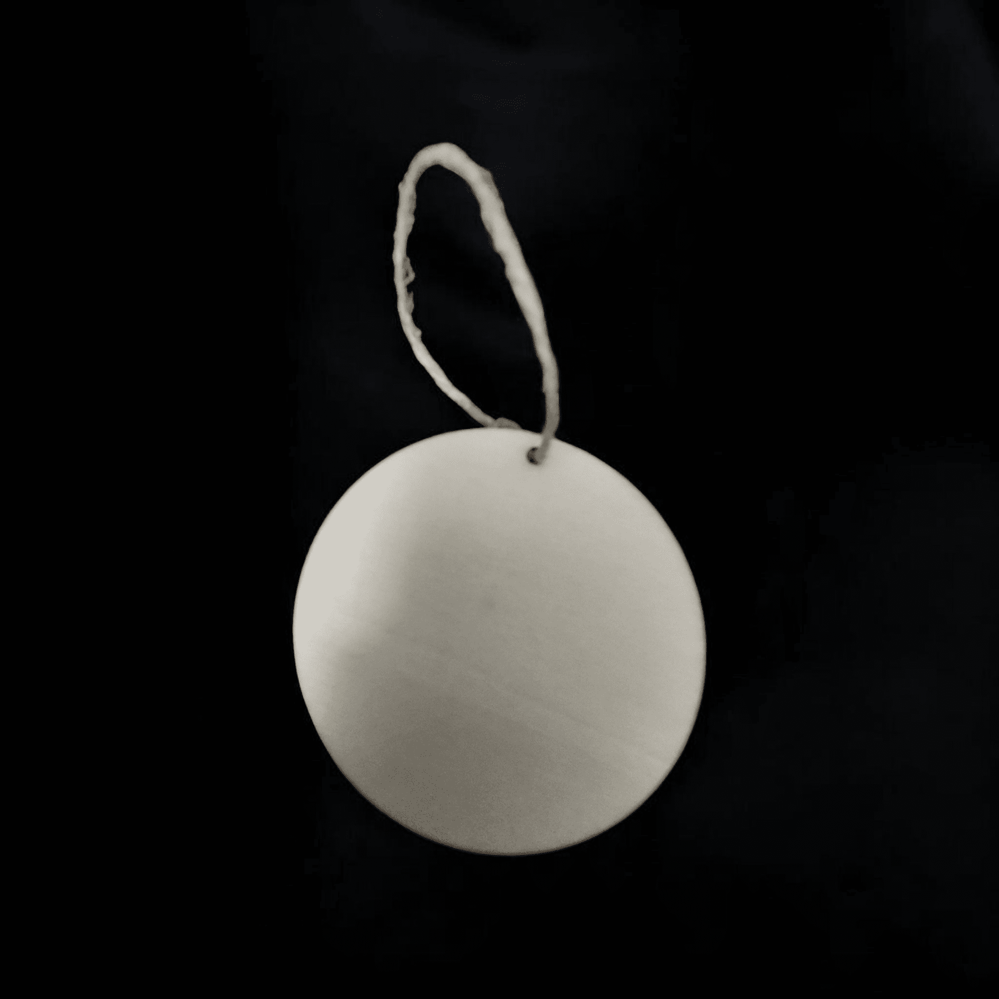 White circular tag with string on black background.