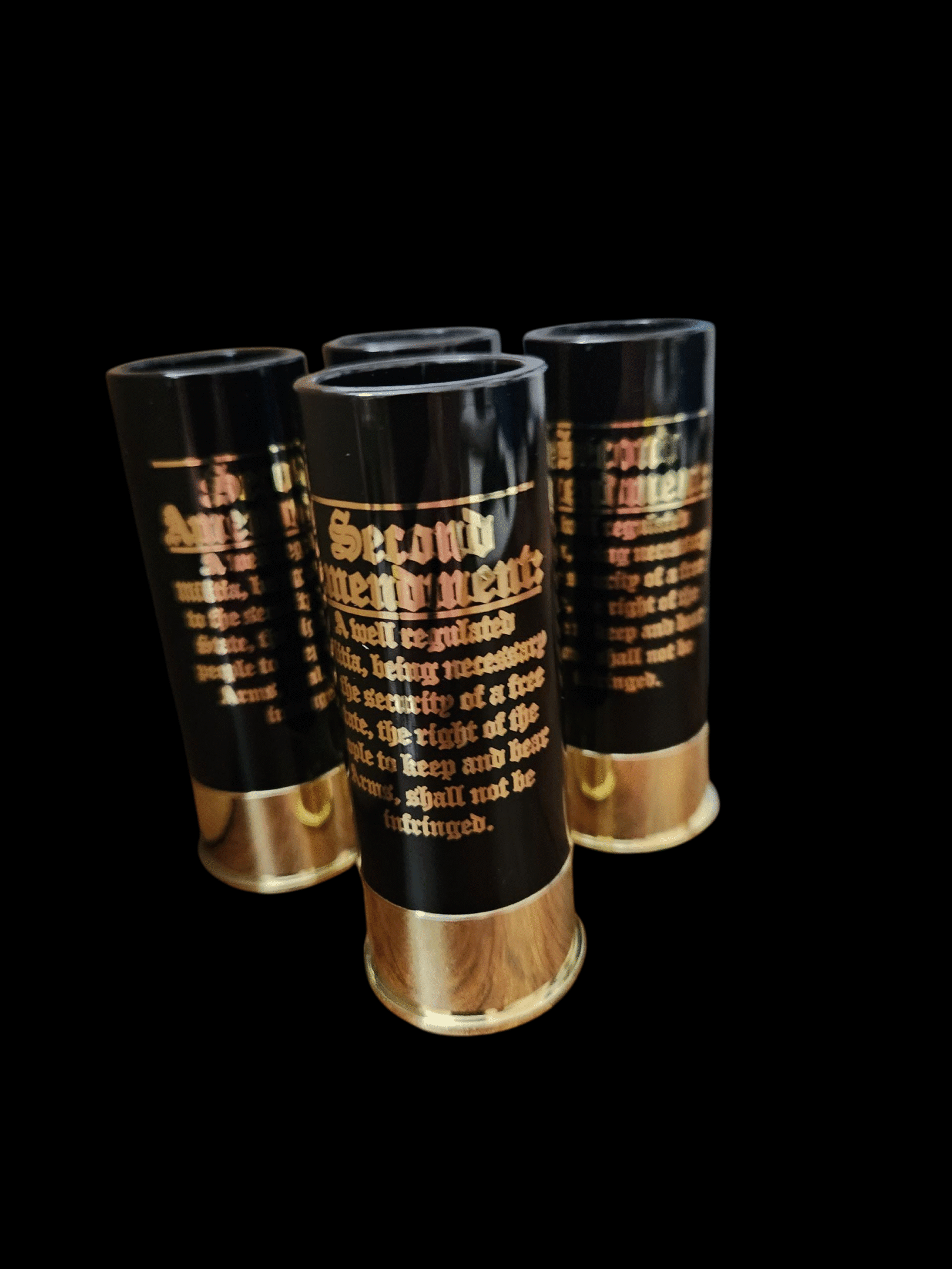 Three black and gold cylindrical containers with text on them.