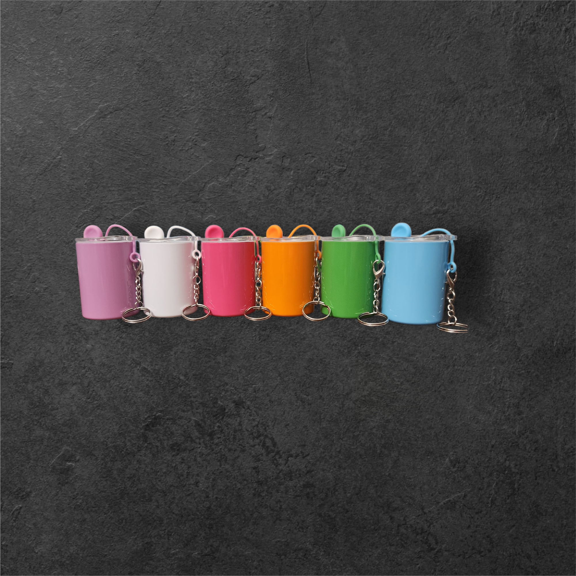 Colorful mini spray paint cans lined up on a dark surface.
